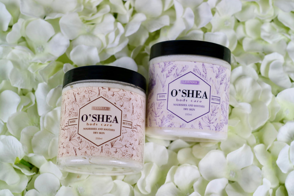 two shea body butter jars on a bed of flowers